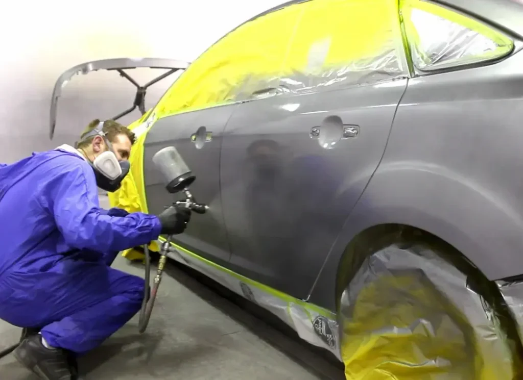 Technician spray painting car.