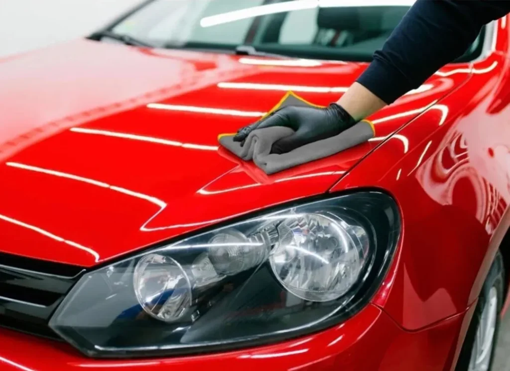 Hand sanding red car.